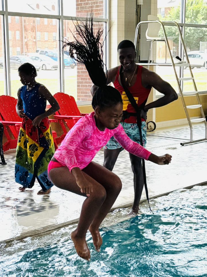 A girl jumping into a swimming pool.